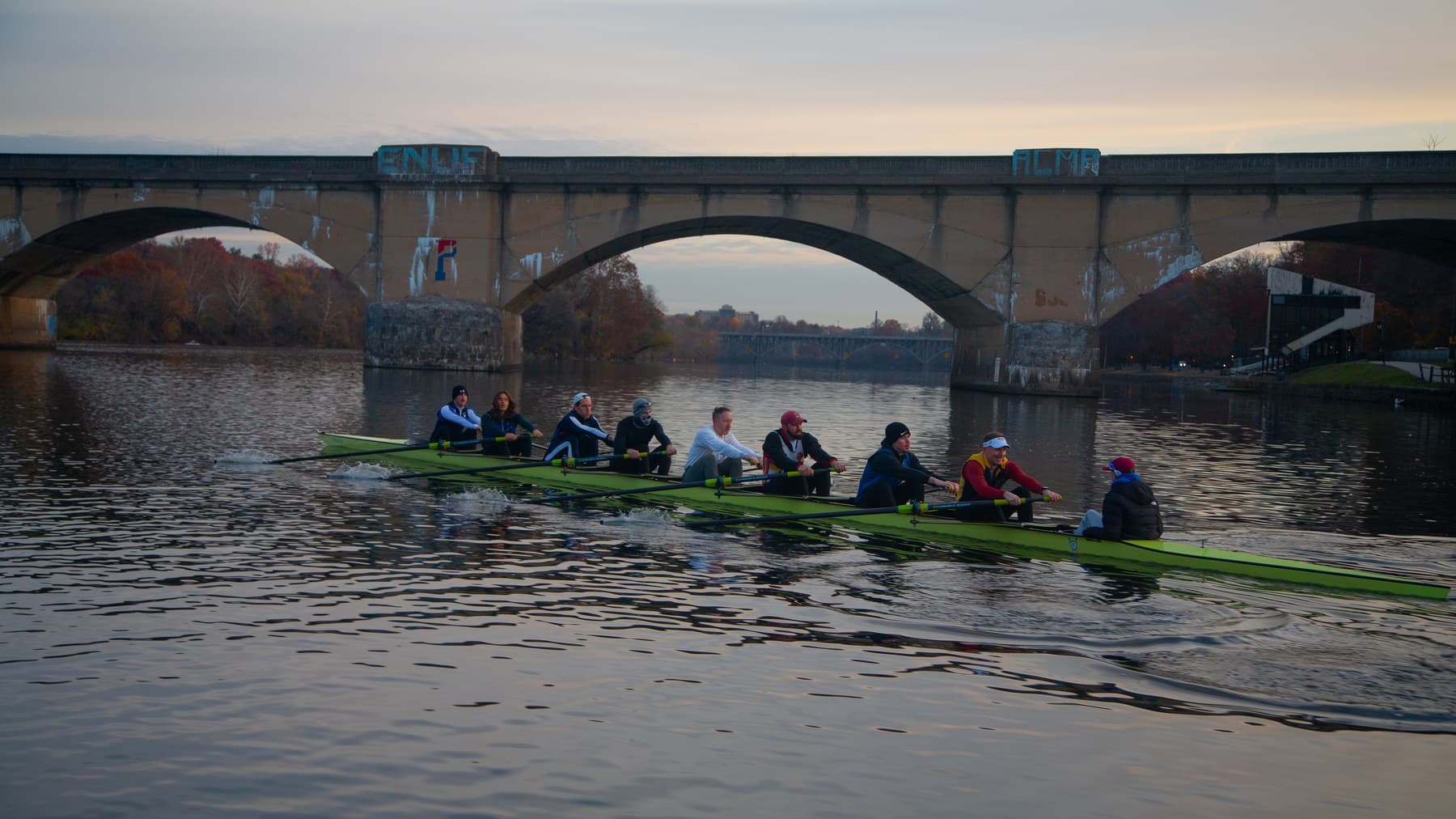 A Fairmount eight rowing under a stone bridge on the Schuylkill River
