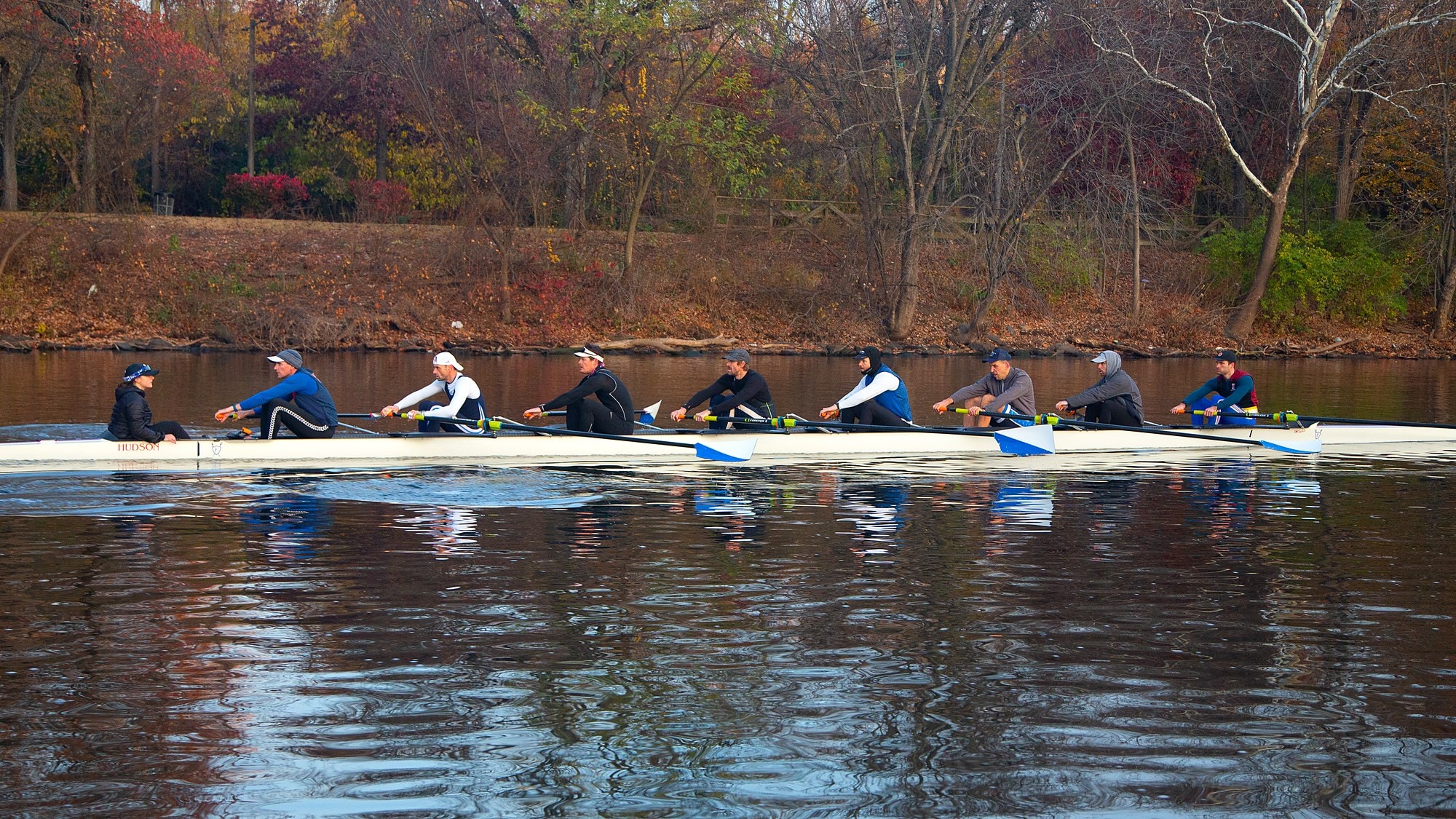 A Fairmount eight rowing along the far bank in the fall